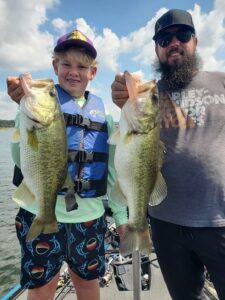 Father and son holding two largemouth bass caught on Lake Travis during a guided fishing trip in August 2025.