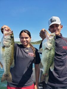 Two clients holding largemouth bass caught at Stillhouse Hollow Lake in September 2025. One fish was caught on a drop-shot finesse worm along submerged vegetation, while the other was landed on a glide bait fished over the grass during late summer conditions.
