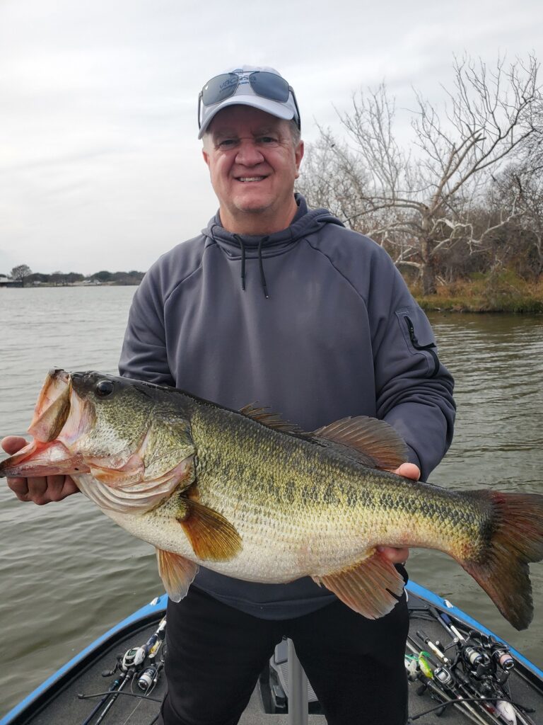 Client holding a double-digit largemouth bass caught at Inks Lake in January 2026 while fishing a pre-spawn staging area.