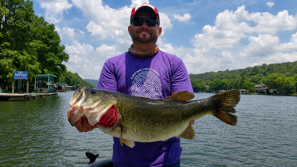 Bassquatch Fishing guide holding a nearly 10-pound largemouth bass caught on Lake Austin using a Neko-rigged creature bait over submerged vegetation.