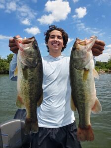 Client holding two largemouth bass caught during a guided fishing trip on Inks Lake using a Neko-rigged creature bait