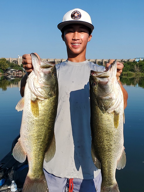 Client holding two largemouth bass caught on Inks Lake while targeting bass feeding on gizzard shad with swimbaits and topwater lures